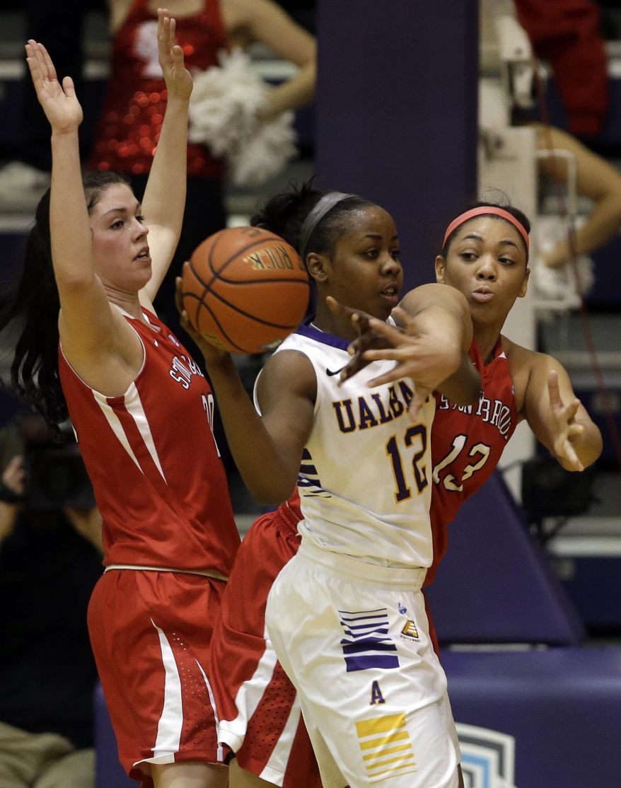 Albany guard Imani Tate (12) is guarded by Stony Brook players Brittany Snow, left, and Sabre Proctor (13) during the first half of an NCAA America East college championship basketball game on Monday, March 10, 2014, in Albany, N.Y. (AP Photo/Mike Groll)
