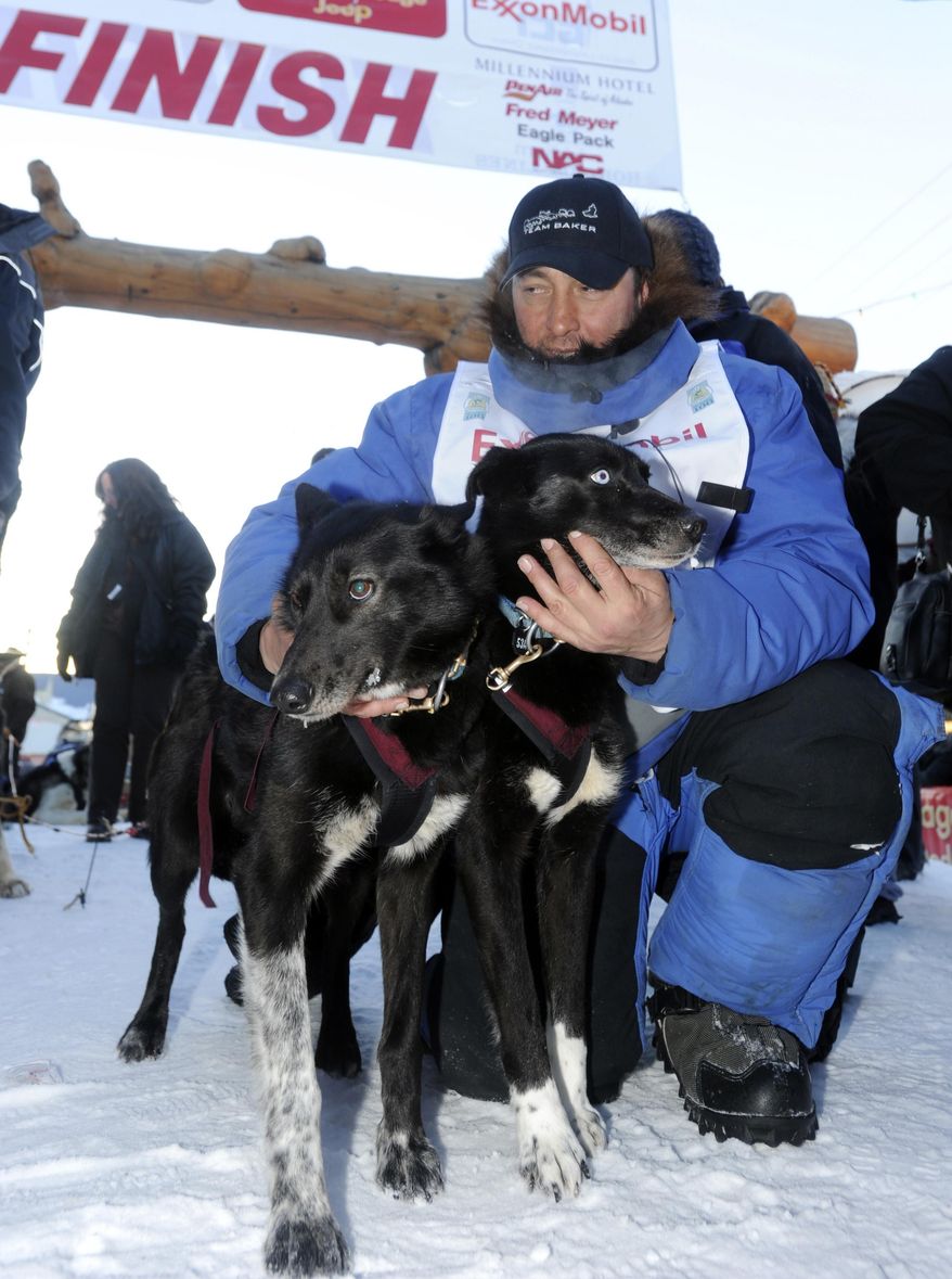 FILE - In this March 15, 2011 file photo, musher John Baker pets his lead dogs Snickers and Velvet after winning the the 2011 Iditarod Trail Sled Dog Race, in Nome, Alaska. Baker holds the record for fastest Iditarod completed, clocking in at the Nome finish line in eight days, 18 hours and 46 minutes. That time was four hours faster than the previous record set nine years earlier by Martin Buser. (AP Photo/The Anchorage Daily News, Bob Hallinen, File)