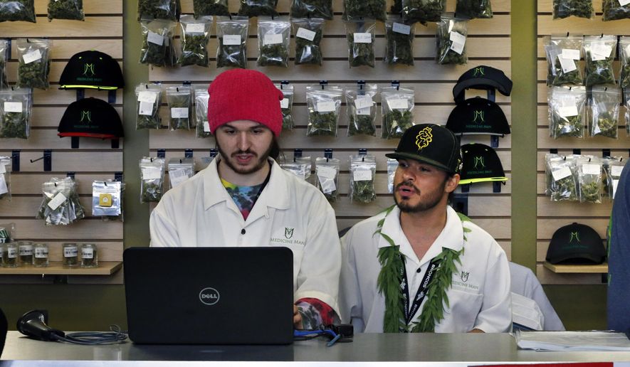 In this Jan. 1, 2014, file photo, employees Chris Broussard, left, and David Marlow, work behind sales counter inside Medicine Man marijuana retail store, which opened as a legal recreational retail outlet in Denver. (AP Photo/Brennan Linsley, File)