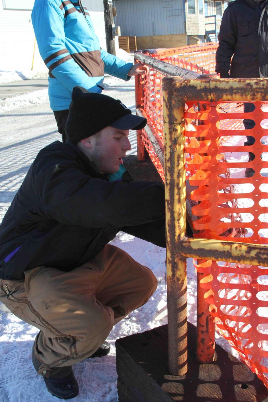Scott Hughes, 19, of Pittsburgh, Pa., hammers nails into place on the chute to the finish line of the Iditarod Trail Sled Dog Race on Sunday, March 9, 2014, in Nome, Alaska. Hughes, a student at the University of Pittsburgh, is helping the city prepare for the finish of the Iditarod as part of a church mission. (AP Photo/Mark Thiessen)