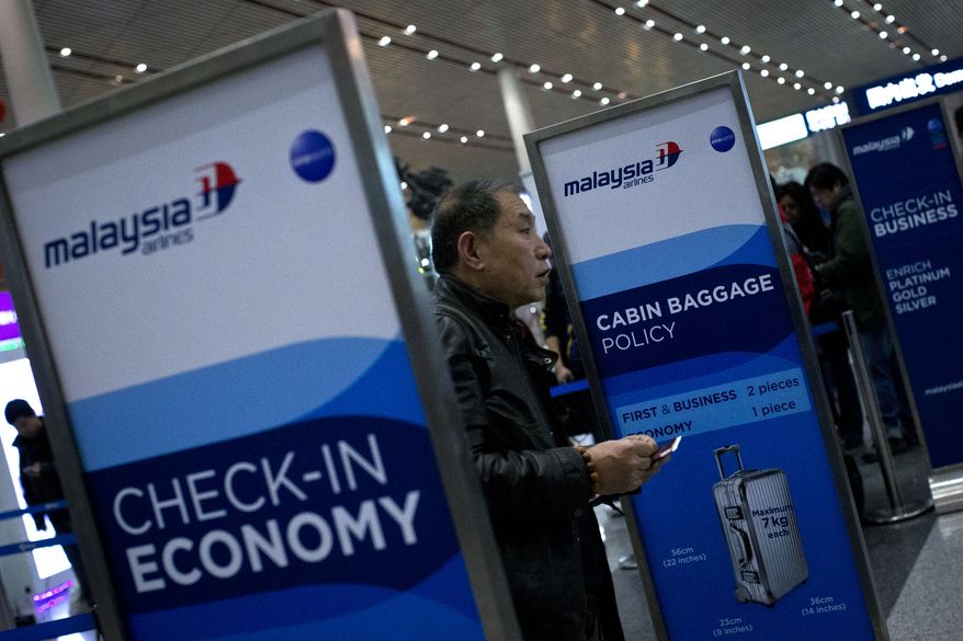 A passenger holds his passport and boarding pass after he checked in his luggage at a Malaysia Airlines check-in counter at Capital International Airport in Beijing, Monday, March 10, 2014. Almost three days after the plane with 239 people on board vanished en route from Kuala Lumpur to Beijing, no debris has been spotted in Southeast Asian waters, hampering efforts to begin the investigation into how the plane disappeared. (AP Photo/Alexander F. Yuan)