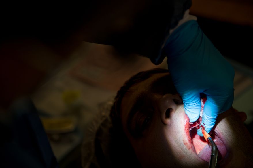 David McCormick of Buena Vista, Va. has all his teeth removed because they were rotting and painful, by Dentist Frank Serio of Bluefield, Va. at the Remote Area Medical's facilities at Southern Virginia University, Buena Vista, Va., Saturday, March 1, 2014. Remote Area Medical Volunteer Corps (RAM) is a Knoxville, Tennessee-based, non-profit, volunteer, airborne medical relief corps that provides free health care, dental care, eye care, veterinary services, and technical and educational assistance to people in remote areas of the United States, and around the world for people that need it. (Andrew Harnik/The Washington Times)