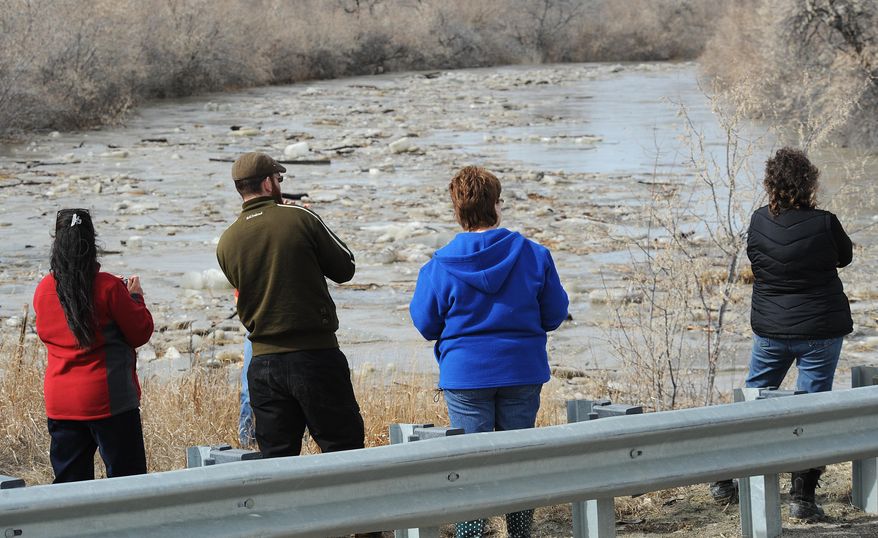 In this photo taken on Sunday, March 9, 2014, bystanders gather to watch an ice jam break up on the Musselshell River in Musselshell, Mont. . A new storm Monday night and Tuesday brought more snow to areas of Montana where hundreds of people have been left cut off by swollen rivers and impassable waterlogged roads. Authorities warned that the new precipitation could make the flooding worse. (AP Photo/Billings Gazette, Larry Mayer)