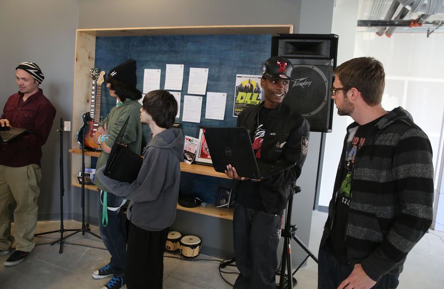 In this Feb. 10, 2014 photo, hip hop artist from the group the Flobots, and Youth on Record co-founder James Laurie, right, talks with music student Dante Hicks, during class at Youth on Record headquarters in Denver. Youth on Record recruits artists, trains them to teach, and puts instruments and professional recording equipment in the hands of young people. It reaches 700 students a year, and currently is working in four Denver high schools and two residential treatment centers. (AP Photo/Brennan Linsley)