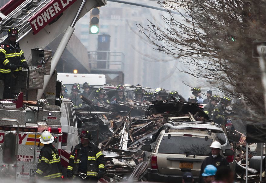 Firefighters continue to investigate and remove debris from an explosion in Harlem, Wednesday, March 12, 2014 in New York. A gas leak triggered an explosion that shattered windows a block away, rained debris onto elevated commuter railroad tracks close by, cast a plume of smoke over the skyline and sent people running into the streets. (AP Photo/Bebeto Matthews)