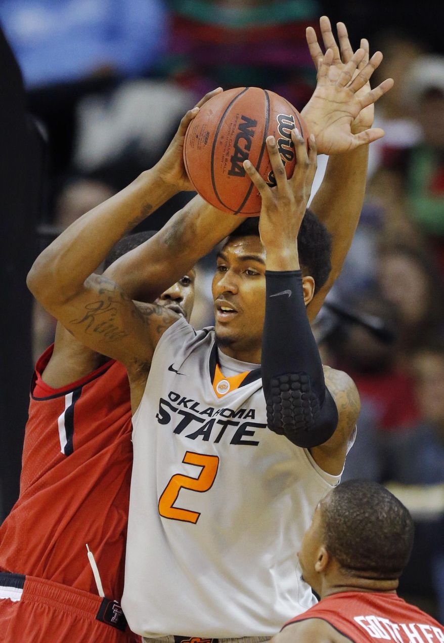 Oklahoma State forward Le'Bryan Nash (2) passes to a teammate while covered by Texas Tech forward Jordan Tolbert, back, during the first half of an NCAA college basketball game in the Big 12 men's tournament in Kansas City, Mo., Wednesday, March 12, 2014. (AP Photo/Orlin Wagner)