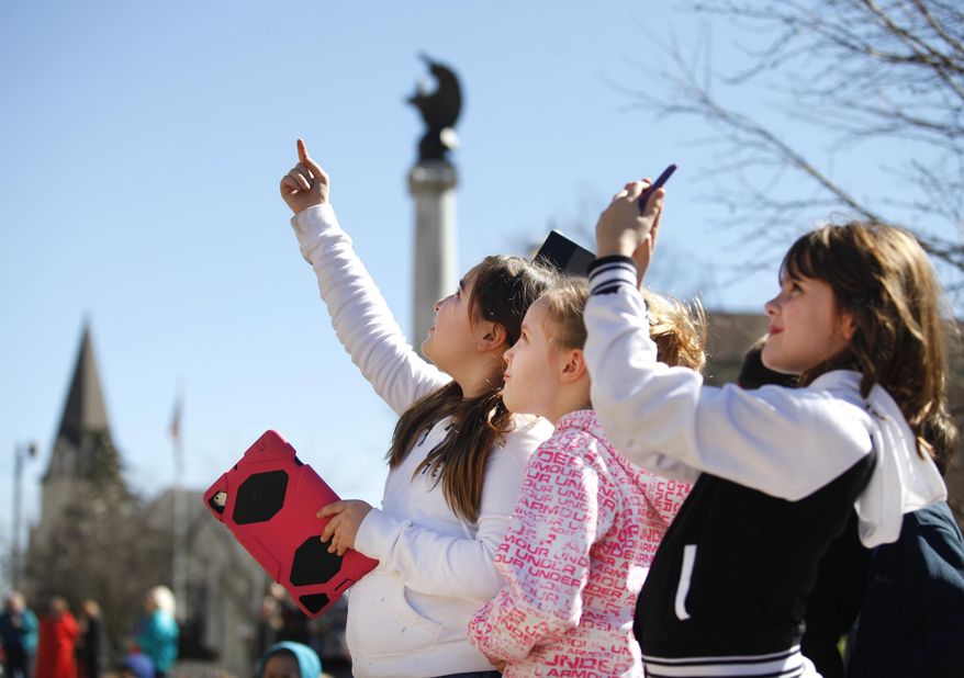 Seton Catholic School students take photos of the Chief Wapello statue being secured to the top of the Wapello County Court, Thursday, March 13, 2014. The students were among the large crowd of people that gathered to watch the event. (AP Photo/The Ottumwa Courier, Lynnette Oostmeyer)