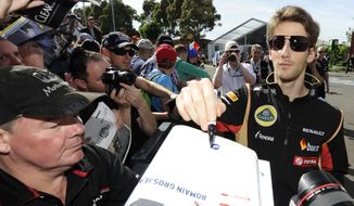 Lotus driver Romain Grosjean of France signs a fan&#39;s race program ahead of the Australian Formula One Grand Prix at Albert Park in Melbourne, Australia, Thursday, March 13, 2014. (AP Photo/Andrew Brownbill)
