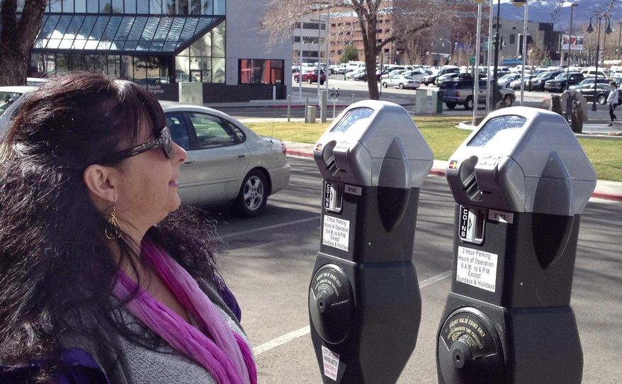 In this photo taken on Tuesday, March 11, 2014, Lisa Arteaga strains to see the screen on a parking meter in downtown Reno, Nev. City officials are cutting several inches off parking meter posts that are too tall for short people who strain to read the meter. (AP Photo/The Reno Gazette-Journal, Anjeanette Damon) NO SALES; NEVADA APPEAL OUT; SOUTH RENO WEEKLY OUT
