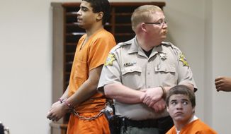 In this photo shot through a courtroom door, defendant Chancey Luna, left, is led from the courtroom following a hearing in Duncan, Okla., Wednesday, March 12, 2014. At right is defendant Michael Jones. Both are charged in the murder of Australian Christopher Lane. (AP Photo/Sue Ogrocki)