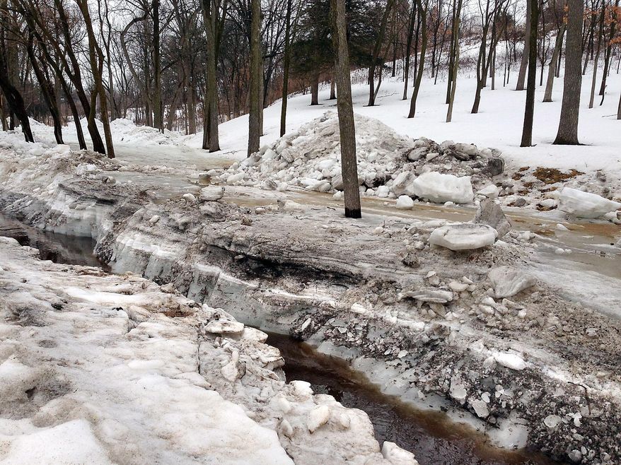 In this photo taken on Tuesday March 11, 2014, water flows through Sand Lake Coulee Creek in the town of Onalaska, Wis., after crews used dynamite to help clear up to five feet of ice. After the blast, crews dug out the ice and created a channel for the water. (AP Photo/The La Crosse Tribune, Chris Hubbach)