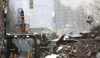 A firefighter applies water to rubble a day after a gas leak-triggered explosion, Thursday, March 13, 2014, in East Harlem, New York. Rescuers working amid gusty winds, cold temperatures and billowing smoke pulled additional bodies Thursday from the rubble of two apartment buildings that collapsed Wednesday. (AP Photo/Julio Cortez)