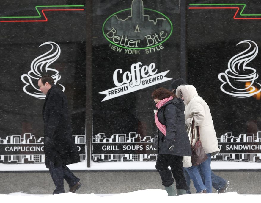 Pedestrians walk through blowing snow on Thursday, March 13, 2014, in Albany, N.Y. Bitter cold temperatures return after a winter storm dumped up to six inches of snow and ice on the Capital Region. (AP Photo/Mike Groll)