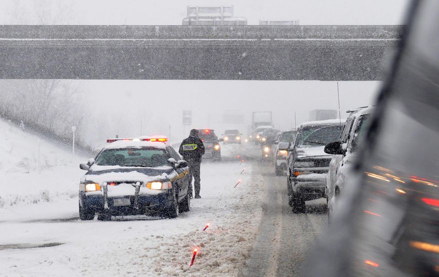 A New York State trooper places flares along the Thruway entrance ramp from I-81 northbound where a tractor trailer was disabled on March 12, 2014 in Syracuse, N.Y. Bitter cold has returned to upstate New York on the heels of the blizzard that dumped 1½ feet of snow on western areas. The National Weather Service says high winds and temperatures in the teens and single digits will drive the wind chill well below zero Thursday, a day after a blizzard closed schools and highways in most of the western half of the upstate region. (AP Photo/The Syracuse Newspapers, Lauren Long) NO SALES