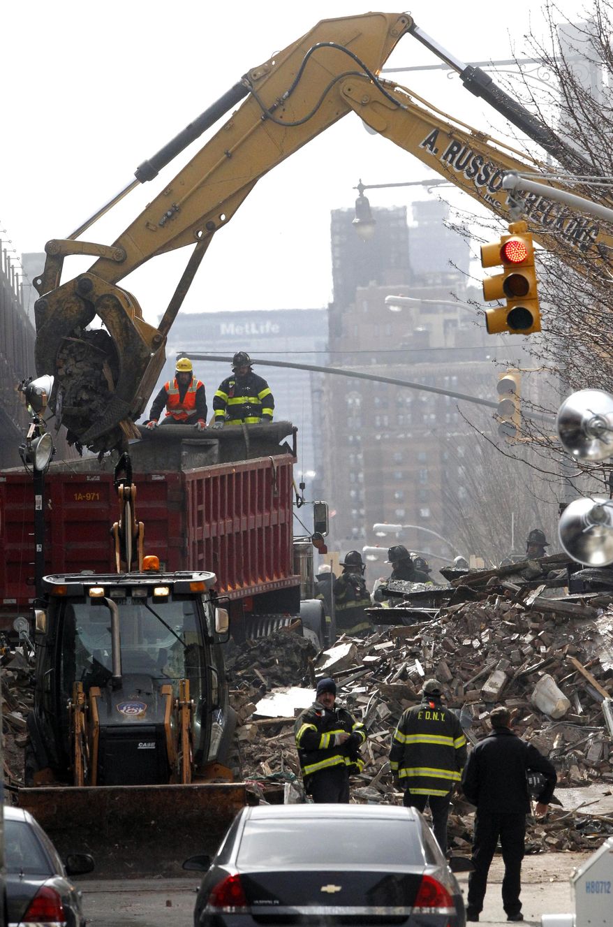 Debris is removed from a mound of rubble a day after a gas leak-triggered explosion, Thursday, March 13, 2014, in East Harlem, New York. Rescuers working amid gusty winds, cold temperatures and billowing smoke pulled additional bodies Thursday from the rubble of two apartment buildings that collapsed Wednesday. (AP Photo/Julio Cortez)