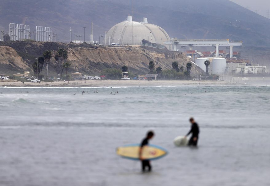 FILE - In this June 7, 2013 file photo, surfers pass in front of the San Onofre nuclear power plant in San Onofre, Calif. More than two years after the San Onofre nuclear power plant stopped production, state regulators planned to make a major decision toward filling the hole left as they consider a proposal on Thursday March 13, 2014. The proposal would allow the plant's co-owners to find replacement power. (AP Photo/Gregory Bull, File)