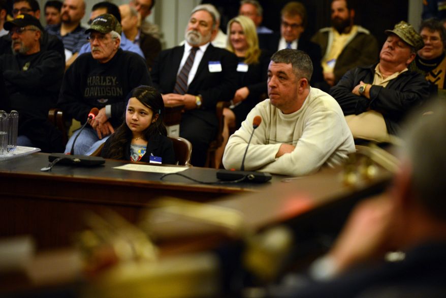 Nine-year-old Shyanne Roberts, left, a nationally sponsored competitive shooter from Franklinville NJ, speaks against the proposed limit on magazine rounds at the statehouse. Her father Dan is at right. (AP Photo/Northjersey.com, Michael Karas)
