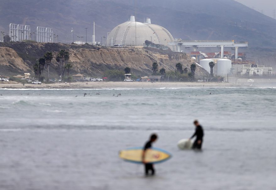 FILE - In this June 7, 2013 file photo, surfers pass in front of the San Onofre nuclear power plant in San Onofre, Calif. More than two years after the San Onofre nuclear power plant stopped production, state regulators planned to make a major decision toward filling the hole left as they consider a proposal on Thursday March 13, 2014. The proposal would allow the plant's co-owners to find replacement power. (AP Photo/Gregory Bull, File)