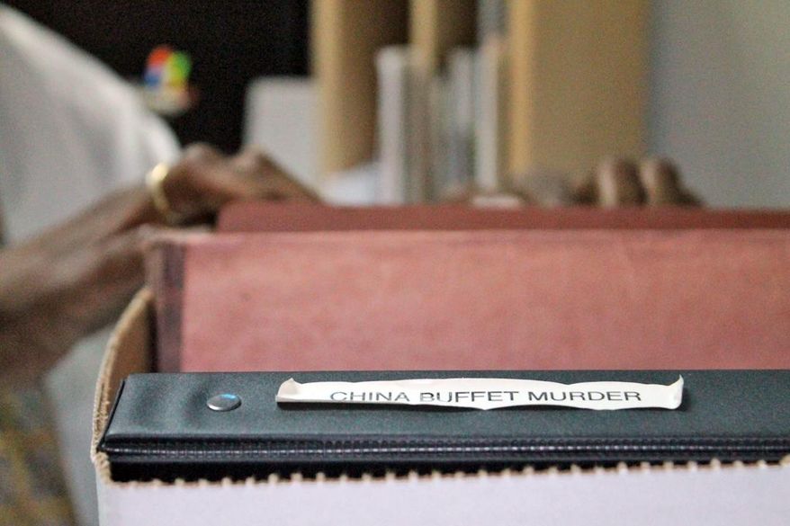 Sgt. Gene Williams, "cold case" investigator with the Sumter Police Department, flips through the evidence file labeled the "China Buffet Murder." on March 9, 2014 in Sumter, S.C. On June 9, 2000, two masked men burst into the buffet late one evening and shot Guang Liang "Eric" Lin dead while he was folding silverware on a dining-area table. Sumter police detectives are still trying to solve the case. (AP Photo/Bristow Marchant)