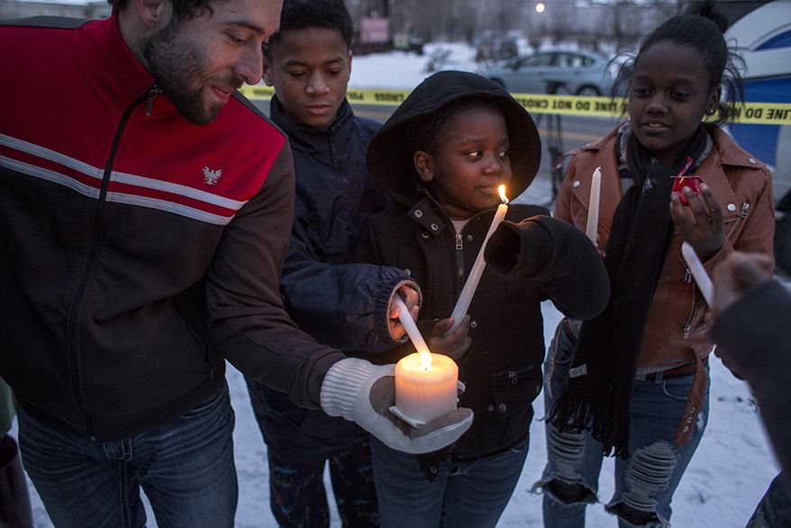 James Laginess, left, lights candles during a vigil at the site of the latest fire at the Heidelberg Project in Detroit, Thursday, March 13, 2014. A March 7 fire destroyed a house covered in stuffed animals and dolls that was part of the Heidelberg Project. It was the latest casualty in a 10-month string of suspicious fires at houses that are part of the interactive outdoor art installation. Tyree Guyton founded the Heidelberg Project on Detroit's east side in 1986 as a response to urban decay. (AP Photo/The Saginaw News, Katie Bailey) ALL LOCAL TV OUT; LOCAL TV INTERNET OUT