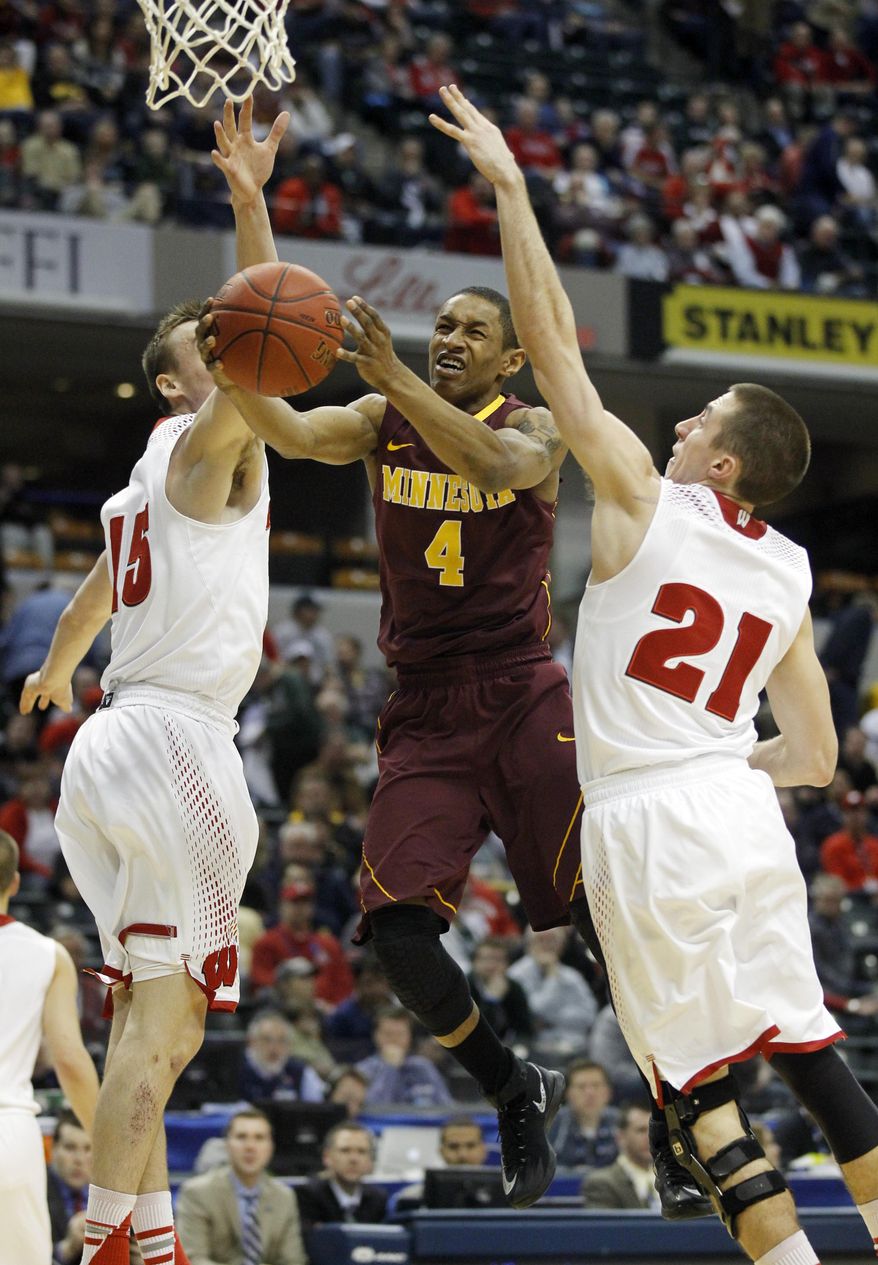 Minnesota guard Deandre Mathieu (4) goes up for a shot between Wisconsin forward Sam Dekker (15) and guard Josh Gasser (21) in the first half of an NCAA college basketball game in the quarterfinals of the Big Ten Conference tournament Friday, March 14, 2014, in Indianapolis. (AP Photo/Kiichiro Sato)