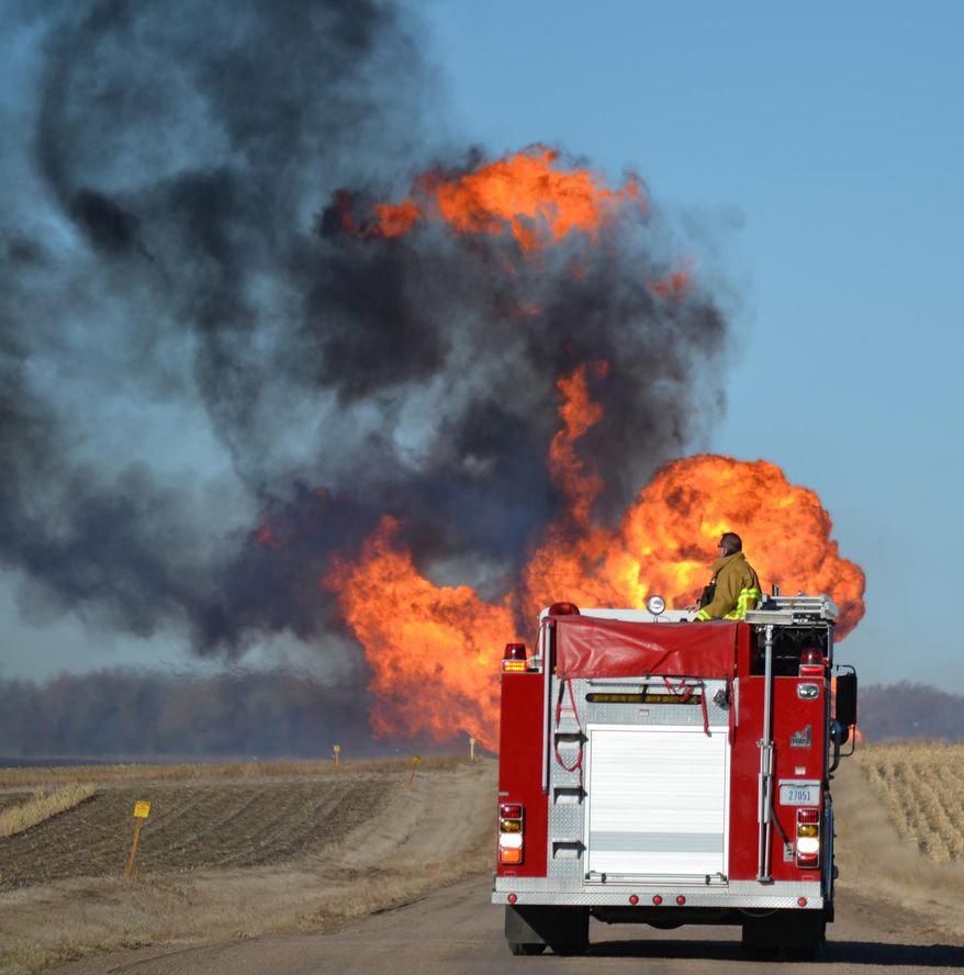 A Nickerson firefighter watches the flames from a natural gas pipeline fire on Friday, March 14, 2014 north of Fremont. The line erupted about 8:30 a.m. Friday near the intersection of county roads 20 and O, about six miles north of Fremont. No damage to any structures has been reported. Firefighters from four departments were waiting nearby for workers to turn off the gas flow. The flames towered dozens of feet into the sky, and the heat kept firefighters from getting close enough to see what caused the blast. (AP Photo/The Tribune, Chris Zavadil)