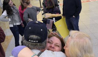 Lisa Bundy, foreground center, of Montgomery, Ala., hugs her father, Wayne Munsch, and friend Pat Creppel, both of New Orleans, upon returning to American soil, Friday, March 14, 2014, at Hartsfield Jackson Atlanta International Airport, in Atlanta. Lisa and daughter Nastia returned from Ukraine after finalizing Nastia&#x27;s adoption there. (AP Photo/AL.com, Julie Bennett)