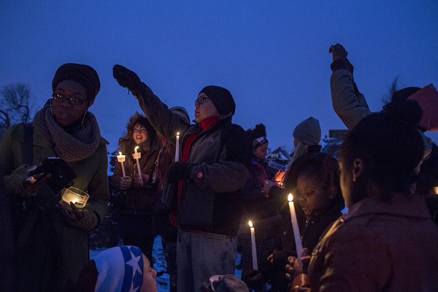 Attendees raise their hands and candles during a vigil at the site of the latest fire at the Heidelberg Project in Detroit, Thursday, March 13, 2014. A March 7 fire destroyed a house covered in stuffed animals and dolls that was part of the Heidelberg Project. It was the latest casualty in a 10-month string of suspicious fires at houses that are part of the interactive outdoor art installation. Tyree Guyton founded the Heidelberg Project on Detroit's east side in 1986 as a response to urban decay. (AP Photo/The Saginaw News, Katie Bailey) ALL LOCAL TV OUT; LOCAL TV INTERNET OUT