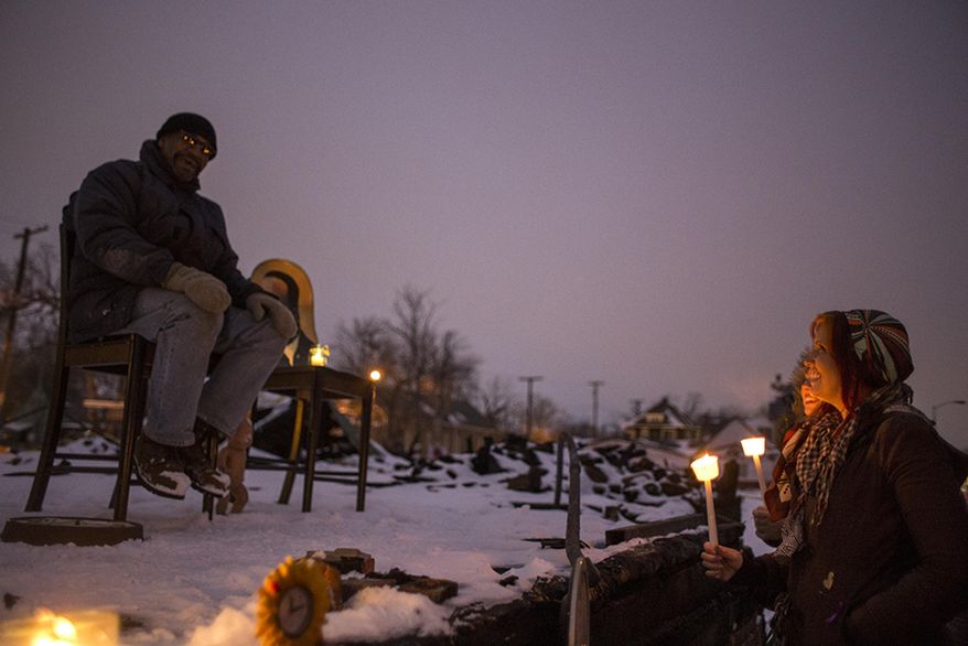 Sam Deniston, right, of Detroit, talks with Heidelberg Project artist and founder Tyree Guyton at a vigil at the site of the latest fire at the Heidelberg Project in Detroit, Thursday, March 13, 2014. A March 7 fire destroyed a house covered in stuffed animals and dolls that was part of the Heidelberg Project. It was the latest casualty in a 10-month string of suspicious fires at houses that are part of the interactive outdoor art installation. Guyton founded the Heidelberg Project on Detroit's east side in 1986 as a response to urban decay. (AP Photo/The Saginaw News, Katie Bailey) ALL LOCAL TV OUT; LOCAL TV INTERNET OUT