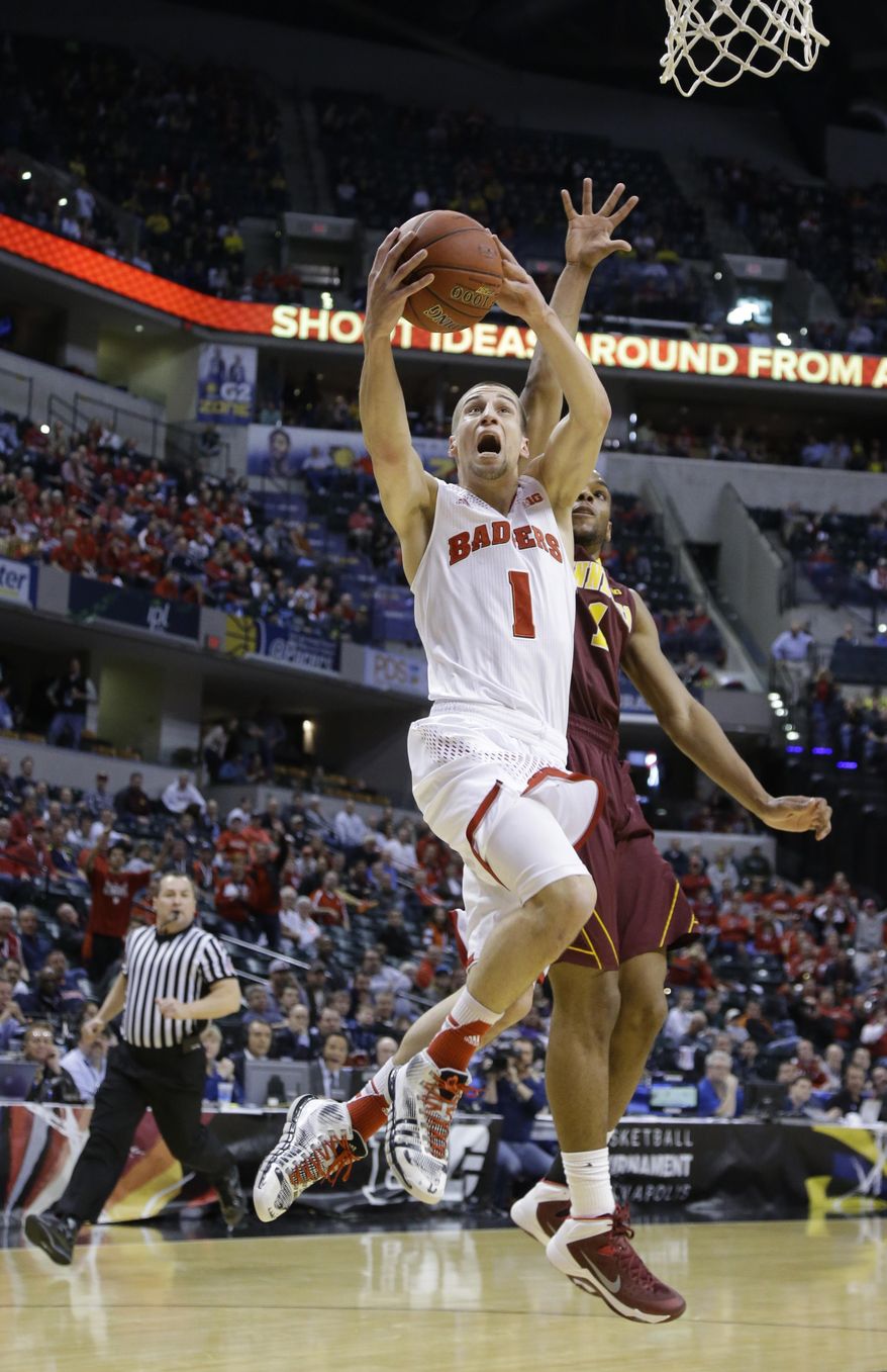 Wisconsin guard Ben Brust (1) goes up for a shot against Minnesota guard Andre Hollins (1) in the first half of an NCAA college basketball game in the quarterfinals of the Big Ten Conference tournament Friday, March 14, 2014, in Indianapolis. (AP Photo/Michael Conroy)
