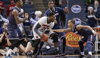 Louisville forward Montrezl Harrell (24) drives between Connecticut&#39;s Phillip Nolan, left, DeAndre Daniels, center, and Shabazz Napier, right, during the first half of an NCAA college basketball game in the finals of the American Athletic Conference men&#39;s tournament Saturday, March 15, 2014, in Memphis, Tenn. (AP Photo/Mark Humphrey)