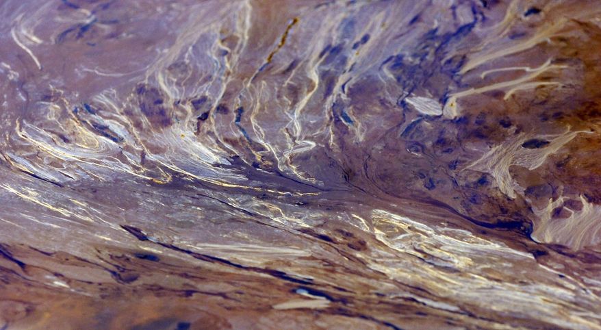 A mixture of crude and weathered oil floats atop water in a swamp near Aliceville, Ala., on Wednesday, May 5, 2014. A train carrying nearly 3 million gallons of oil crashed at the site in November 2013, resulting in the pollution. Environmental regultors say cleanup and containment work is continuing, but critics contend the Alabama accident and others show the danger of transporting large amounts of oil in tanker trains. (AP Photo/Jay Reeves)