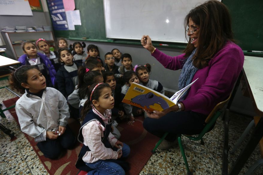 In this picture taken on Wednesday, March 5, 2014, Lebanese teacher Rajaa Bshara, right, reads a story for Syrian refugee students at a mixed Lebanese-Syrian students classroom at a Lebanese public school in Beirut, Lebanon. More than 2 million of those who should be in school remain in Syria, where classrooms have been bombed, used as shelters or turned into military barracks. Another 300,000 Syrian children don’t attend school in Lebanon, along with some 93,000 in Jordan, 78,000 in Turkey, 26,000 in Iraq and 4,000 in Egypt, UNICEF officials in Geneva said. Those numbers likely are higher, as UNICEF can’t count the children whose parents didn’t register with the United Nations refugee agency. (AP Photo/Hussein Malla)