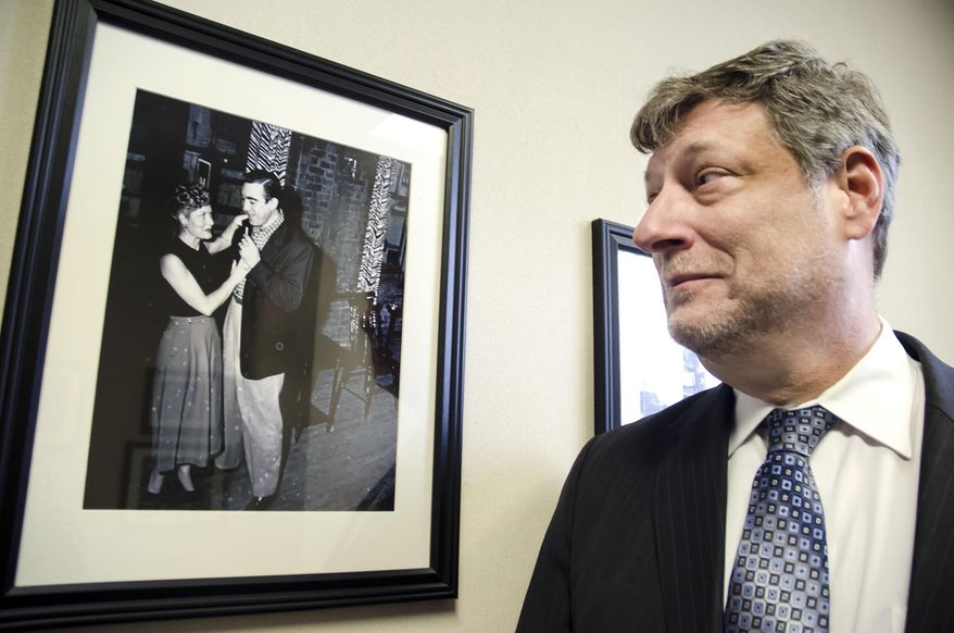 ADVANCE FOR USE SUNDAY, MARCH 16, 2014, AND THEREAFTER - In this March 6, 2014 photo, attorney Michael Manely admires a photo shot around 1947 in Atlanta of actor Anthony Quinn, at Manely's law firm in Marietta, Ga. Photographer Ralph Sosebee Sr. shot the original image that is now on display at the firm. (AP Photo/The Marietta Daily Journal, Jeff Stanton) ATLANTA JOURNAL CONSTITUTION OUT; MAGS OUT; NO SALES