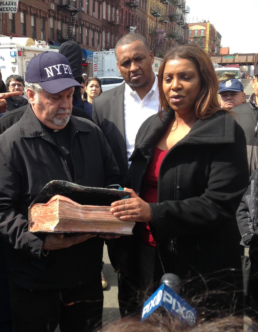 Rick Del Rio, pastor of Abounding Grace church in Manhattan, and New York City Public Advocate Letitia James, display a damaged but intact Bible they said was recovered in the rubble of the Spanish Christian Church, Saturday, March 15, 2014 in New York. The church was in one of the buildings destroyed in the March 12 gas explosion that leveled two building and killed eight people. (AP Photo/Jim Fitzgerald)
