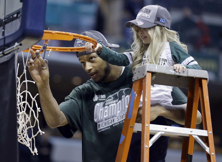 Michigan State forward Adreian Payne, left, cuts the net with Lacey Holsworth, who is battling cancer and has become close to Payne, after Michigan State defeated Michigan 69-55 in an NCAA college basketball game in the championship of the Big Ten Conference tournament on Sunday, March 16, 2014, in Indianapolis. (AP Photo/Michael Conroy)
