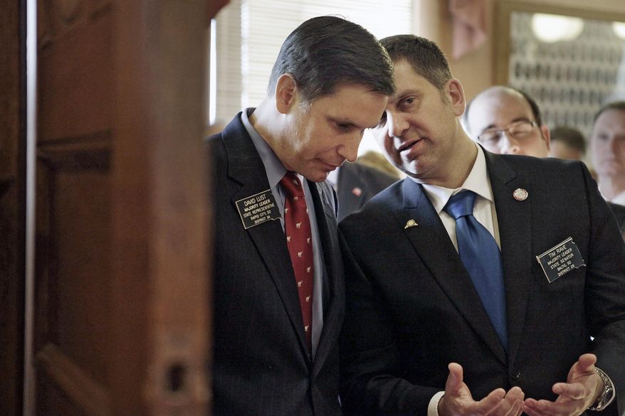 FILE - In this Jan. 14, 2014 file photo House Majority Leader David Lust, left, R-Rapid City, left, and Senate Majority Leader Tim Rave, R-Baltic, talk in the House lobby in Pierre, S.D. An intentionally vague bill introduced by Rave with the intention of overhauling it later in the session has taken an unusual journey through the Legislature _ it was co-opted by another legislator in the process. The increased use of these empty or "vehicle" bills has drawn criticism from the South Dakota Newspaper Association and others for circumventing the usual legislative process. (AP Photo/Rapid City Journal, Chris Huber, File)