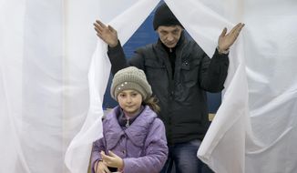 A man and child exit a voting booth after casting a vote in the Crimean referendum in Simferopol, Ukraine, Sunday, March 16, 2014. Residents of Ukraine&#x27;s Crimea region are voting in a contentious referendum on whether to split off and seek annexation by Russia. (AP Photo/Vadim Ghirda)