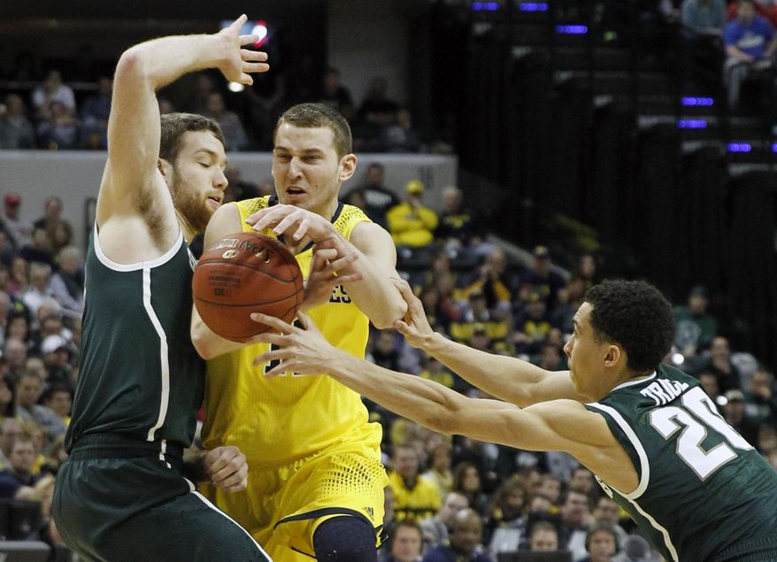 Michigan guard Nik Stauskas, center, loses control of the ball as he is defended by Michigan State forward Matt Costello, left, and guard Travis Trice in the first half of an NCAA college basketball game in the championship of the Big Ten Conference tournament on Sunday, March 16, 2014, in Indianapolis. (AP Photo/Kiichiro Sato)