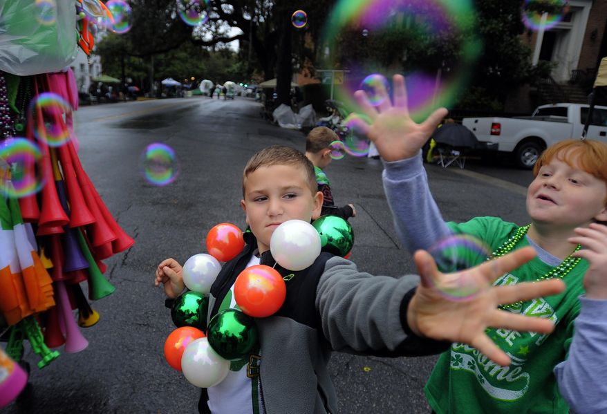 Will Banton, center, and Dylan Browne try to catch bubbles before the start of Savannah's 190-year-old St. Patrick’s Day parade, Monday, March 17, 2014, in Savannah, Ga. Started in 1824 by early Irish immigrants to Georgia, the parade has ballooned into a sprawling street party that makes for one of Savannah's most profitable tourism events. (AP Photo/Stephen B. Morton)