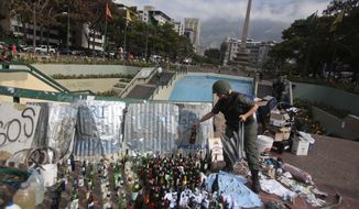A Bolivarian National Guard places a glass bottles with others items allegedly seized from demonstrators after a raid in Plaza Altamira, Caracas, Venezuela, Monday, March 17, 2014. The Bolivarian National Guard conducted raids in the Chacao district this Monday morning vacating the barricades installed there in order to prevent anti-government protests from happening in the area. (AP Photo/Esteban Felix)