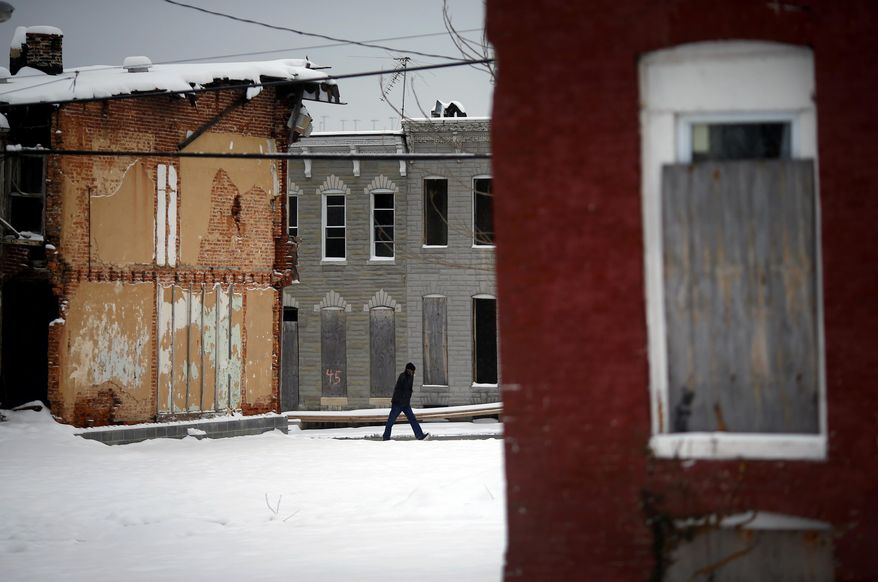 A man walks past blighted row houses as a light snow falls in Baltimore, Monday, March 17, 2014. The winter-weary faced another treacherous morning in parts of the Mid-Atlantic as snow and frigid weather blew in just days before the start of spring. (AP Photo/Patrick Semansky)