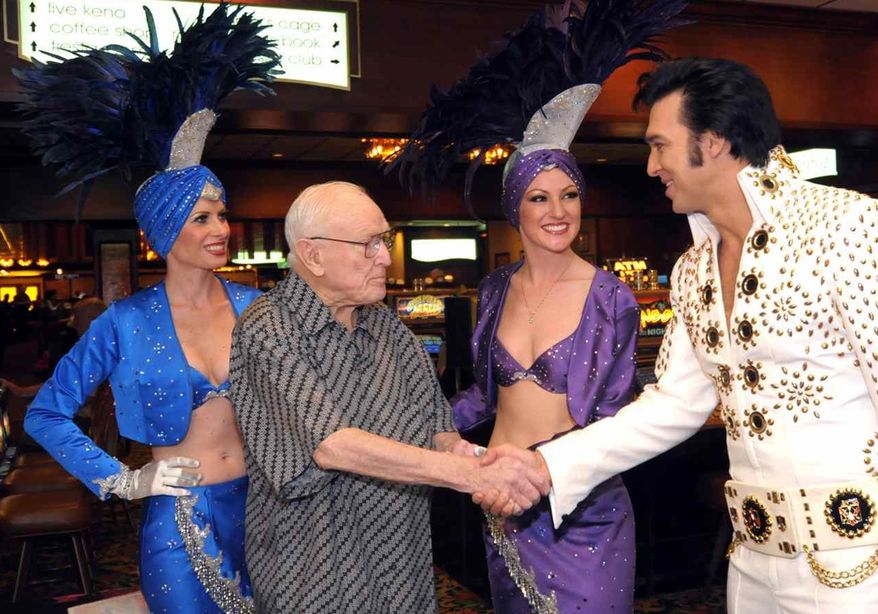 FILE - In this Oct. 24, 2009 file photo provided by the Las Vegas News Bureau, hotel and gaming pioneer Jackie Gaughan is greeted by an Elvis impersonator and showgirls as he celebrates his 89th birthday at the El Cortez Hotel and Casino in downtown Las Vegas. Gaughan, the Las Vegas gambling pioneer who once owned much of the downtown casino market, died Wednesday, March 12, 2014. He was 93. Gaughan is most closely associated with the El Cortez casino, which he bought in 1963. He later transferred ownership of the historic casino, but lived in a penthouse apartment there into his 90s and was known to play poker in the casino almost every day.(AP Photo/Las Vegas News Bureau, Glenn Pinkerton, File)