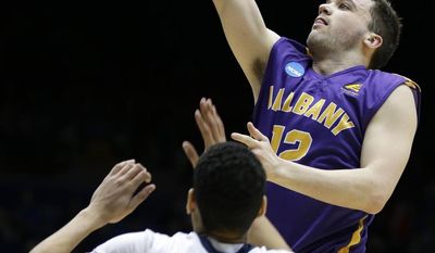 Albany guard Peter Hooley (12) drives against Mount St. Mary&#x27;s guard Julian Norfleet (23) during the first half of a first-round game of the NCAA college basketball tournament, Tuesday, March 18, 2014, in Dayton, Ohio. (AP Photo/Al Behrman)