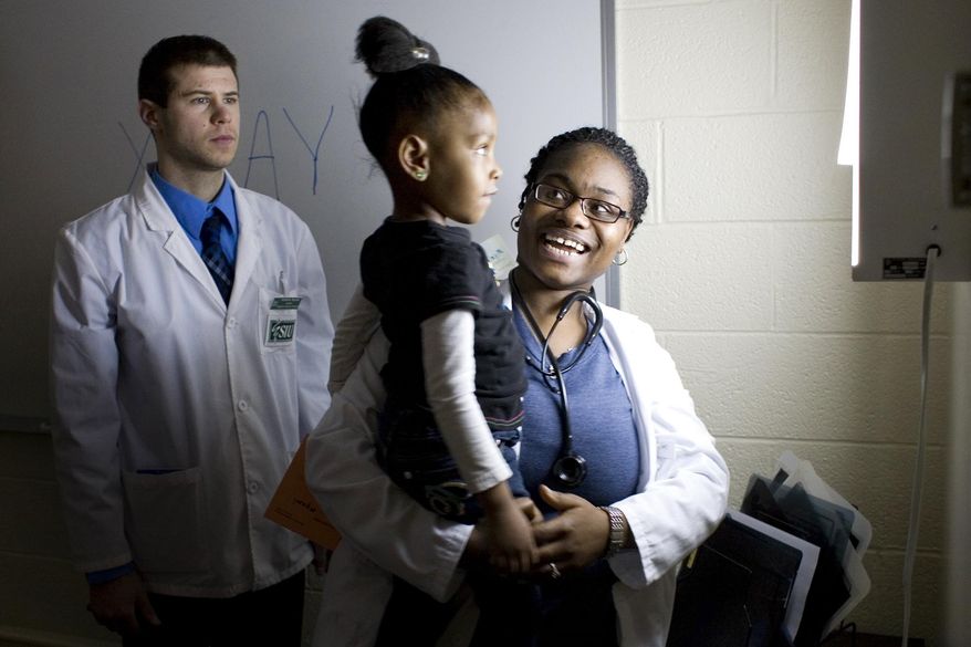 ADVANCE FOR USE SATURDAY, MARCH 22 AND THEREAFTER - In this March 6, 2014 photo, Lauquyta Wilmore and Andrew Bryant, physician assistant graduate students at the Southern Illinois University School of Medicine, go over X-ray's of Myami Rankin's doll "Baby M" during a doll clinic in Carbondale, Ill. The doll clinic gives children the opportunity to observe scary or threatening medical procedures, without being the subject of those procedures. (AP Photo/The Southern, Steve Matzker)