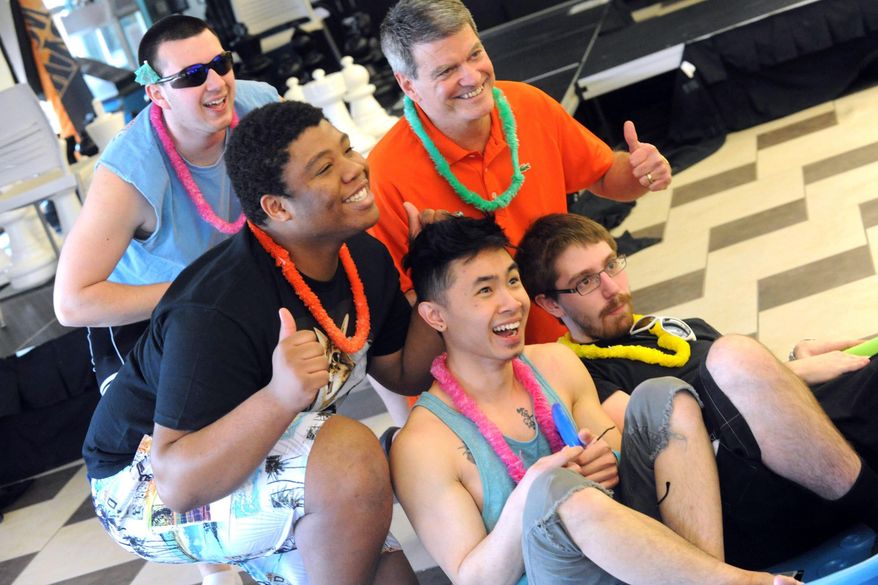 In this Tuesday, March 18, 2014 photo, In orange, Northampton Community College President, Dr. Mark Erickson, back right, joins students as they pose for photographs, during an imaginary beach day in the lounge of the Bethlehem, Pa. school. The students are protesting the cancellation of spring break by wearing flip-flops, bathing suits and tank tops to class. (AP Photo/The Express-Times, Sue Beyer)