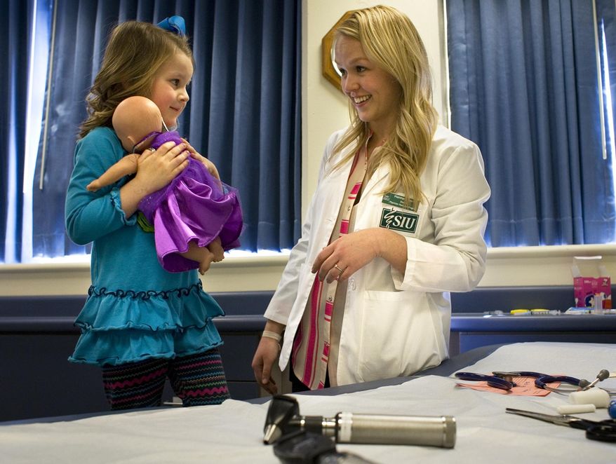 ADVANCE FOR USE SATURDAY, MARCH 22 AND THEREAFTER - In this March 6, 2014 photo, Finley Diemer hugs her baby "Drew" as Hannah Cross, a physicians assistant graduate student at the Southern Illinois University School of Medicine talks about "Drew's" treatment as part of a doll clinic on SIU's campus in Carbondale, Ill. The doll clinic gives children the opportunity to observe scary or threatening medical procedures, without being the subject of those procedures. (AP Photo/The Southern, Steve Matzker)