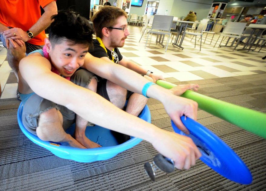 In this Tuesday, March 18, 2014 photo, Northampton Community College students Thoai Luong and Sebastian Paff try out the swimming pool in the lounge of the Bethlehem, Pa. school. The students are protesting the cancellation of spring break by wearing flip-flops, bathing suits and tank tops to class. (AP Photo/The Express-Times, Sue Beyer)