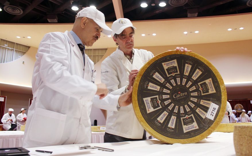 Roberto Castaneda, left, from Argentina, and Max McCalman inspect a wheel of gruyere during the first day of judging for 2014 World Championship Cheese Contest Tuesday, March 18, 2014, in Madison, Wis. Entries in the 2014 World Championship Cheese Contest reached a new record this year, growing five percent to more than 2,600 entries from 22 nations around the world. (AP Photo/Carrie Antlfinger)