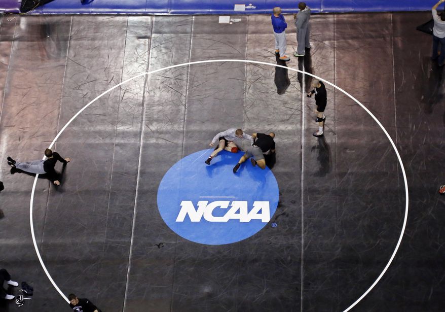 Donald Patrick, left, of Davidson College in Davidson, N.C., works with his coach, Brandon Sinnott, right, on a wrestling mat in Oklahoma City, Wednesday, March 19, 2014, in preparation for the NCAA college wrestling championships. Competition begins March 20. (AP Photo/Sue Ogrocki)